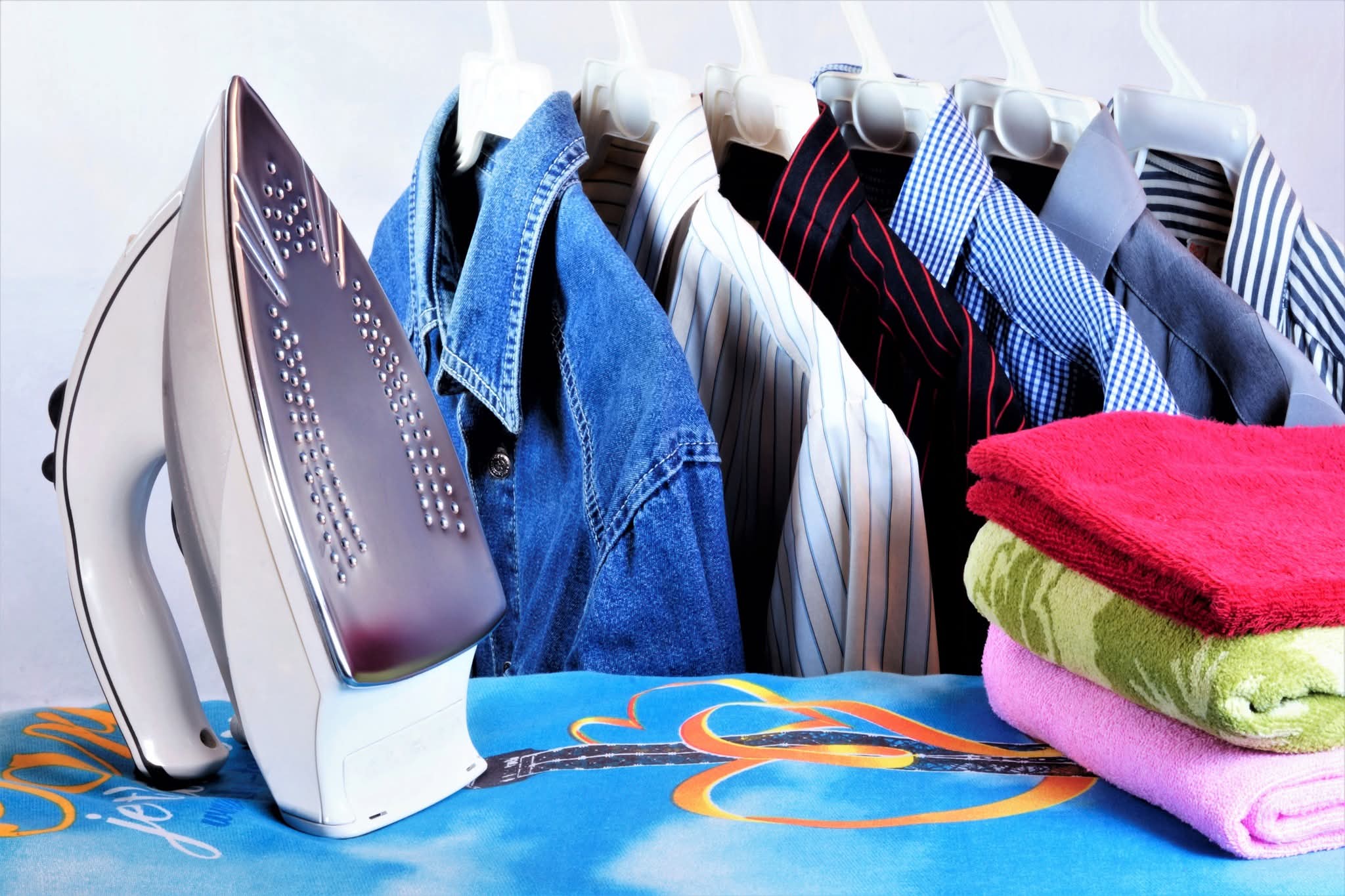 Freshly ironed shirts hanging alongside folded towels